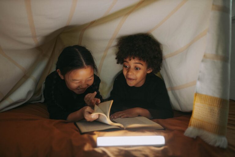 Two children read a book together under a cozy blanket fort, illuminated by soft lighting from Books Like Franklin the Turtle: 10 Best Read-Alike Series