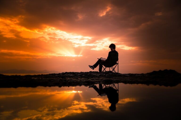 A person reading on a chair by a reflecting pond at sunset in Korgan, Turkey from 15 Reading Challenge Ideas for 2026 to Level Up Your Reading Life