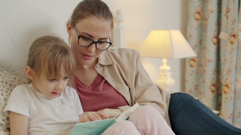 Mother and daughter reading a book together in bed from Reading with Kids: Practical Tips for Families article by Books In Chronological Order