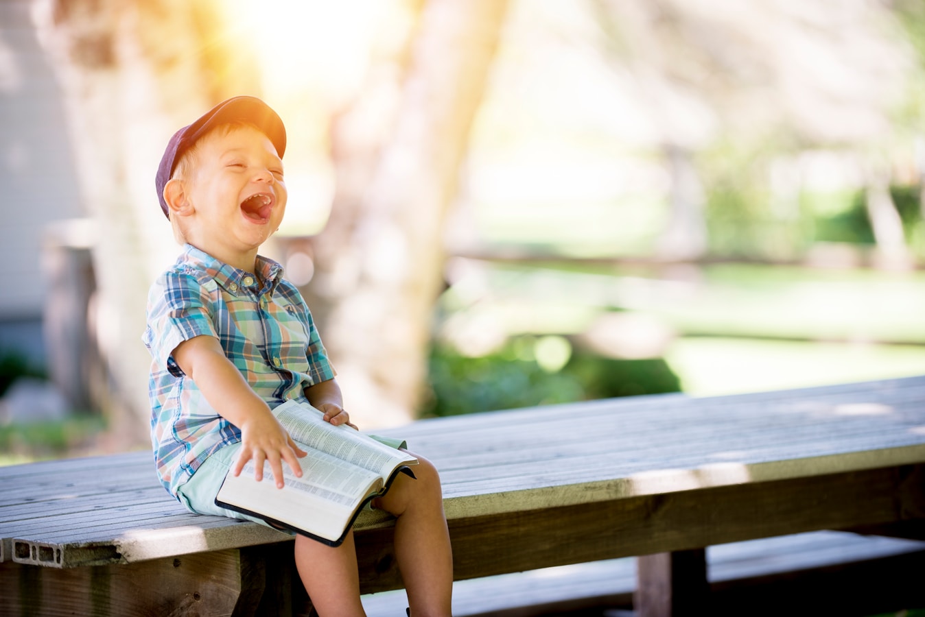 boy sitting on bench while holding a book from What are some Kids’ Books to Ignite Outdoor Adventure Spirit?